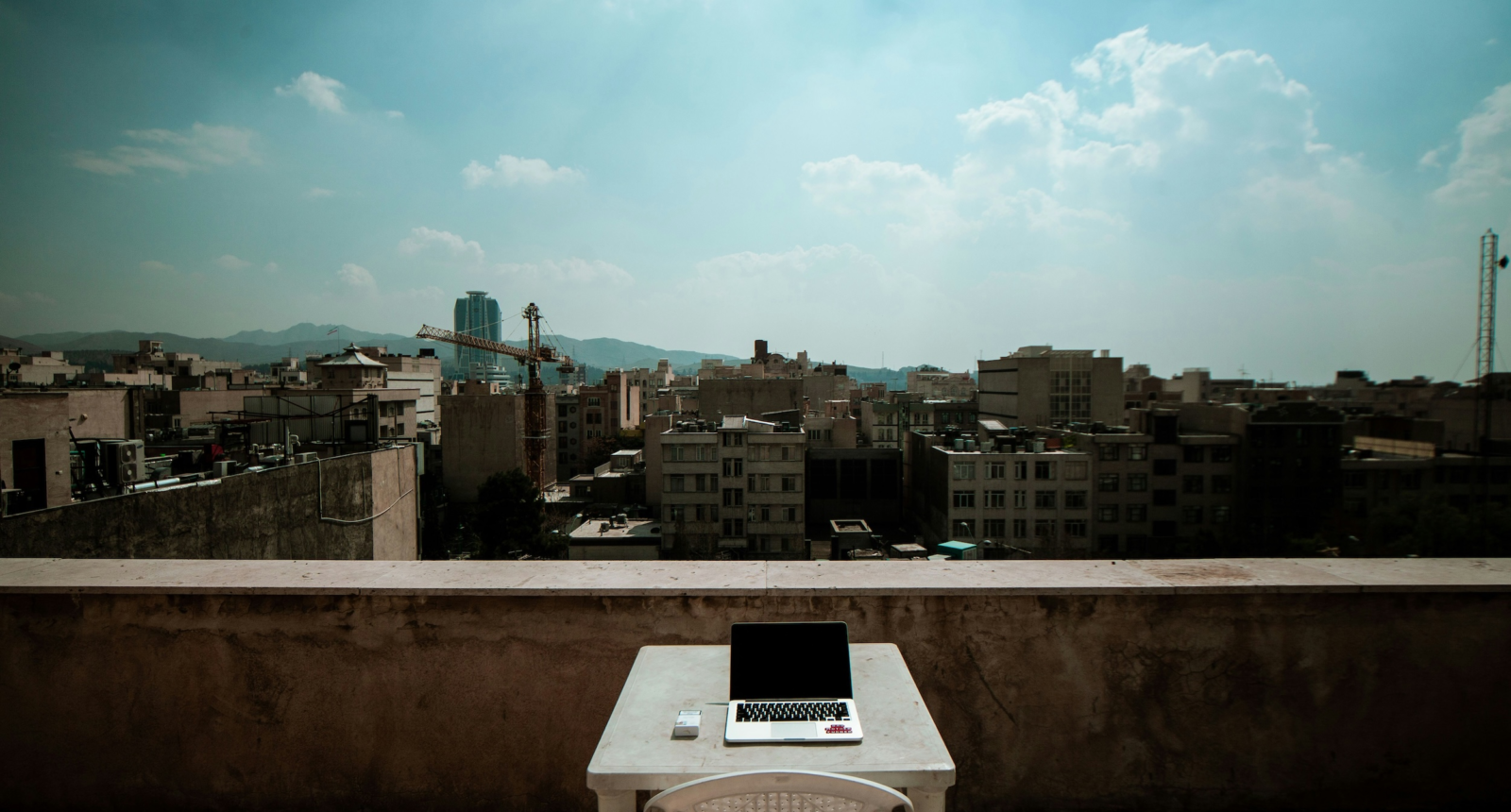A laptop on a rooftop overlooking Tehran. Photo: Ariyan Dv/Unsplash